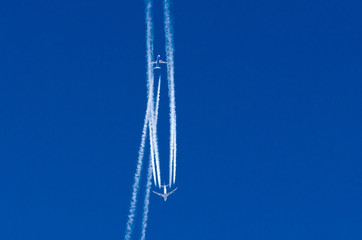 Airplane crosses the contrail of another aircraft against the blue sky.