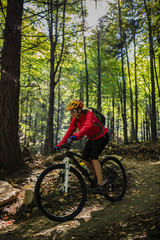 Fototapeta na wymiar Cycling, mountain bikeing woman on cycle trail in autumn forest. Mountain biking in autumn landscape forest. Woman cycling MTB flow uphill trail.