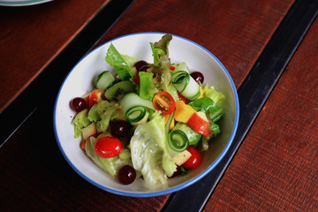 Bowl of healthy fresh fruit salad on wooden table, Delicious salad with mix fruit and vegetable, organic salad for healthy 