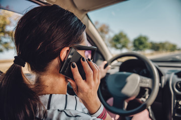 Woman driving car and talking on smart phone - obrazy, fototapety, plakaty