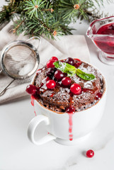Winter, fall healthy breakfast or snack. The idea of a quick treat for Christmas. Chocolate mug cupkake in ceramic cup, with cranberry and sauce, powdered sugar. White marble table, copy space