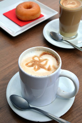 Cup of foamy cappuccino on a plate on a wooden table.