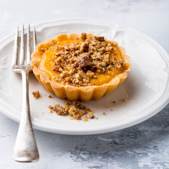 Thanksgiving day concept with homemad pumpkin tartlet, mini pie, on gray stone background. Healthy autumn food.