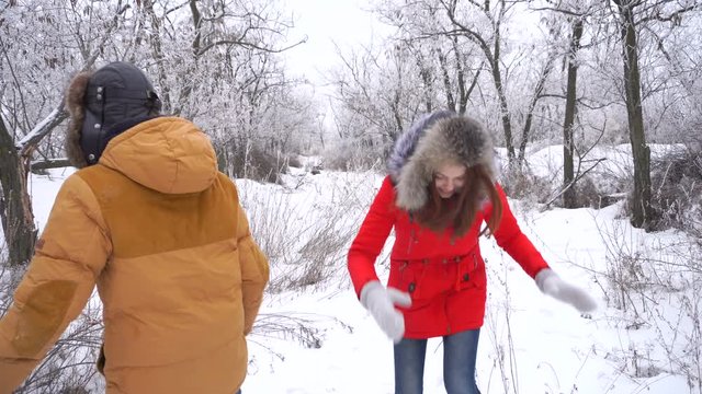 Couple in love. Teenagers on a date in the winter outdoors. The girl and the guy are kissing and fooling around. She throws snow at him. Strong embrace.