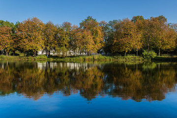 Fototapeta na wymiar Autumnal landscape with colorful trees and their reflecion in water