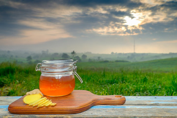 Alternative Medicine with garlic and  honey on wooden table. Beautiful sunrise as background.