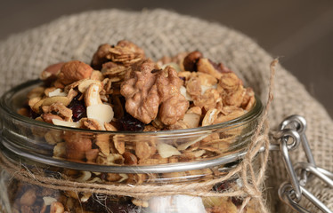 Homemade granola in open glass jar on rustic wooden background
