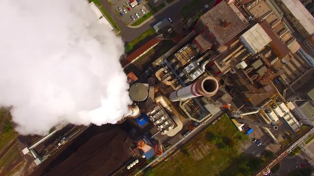 Camera flight over a modern combined heat and power plant. Fuming chimney with sulphur removal unit. Heavy industry from above. Power and fuel generation in European Union. 