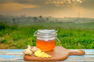 Alternative Medicine with garlic and  honey on wooden table. Beautiful sunrise as background.