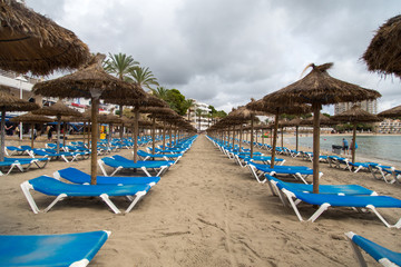 Leere Liegen am Strand an einem regnerischen Tag