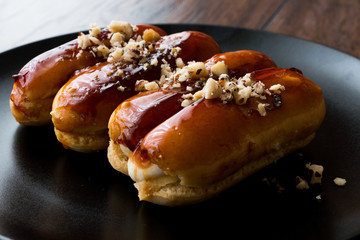 Caramel Eclairs with Hazelnut and cream in black plate.