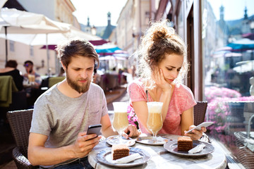 Young couple with smartphones sitting in cafe.