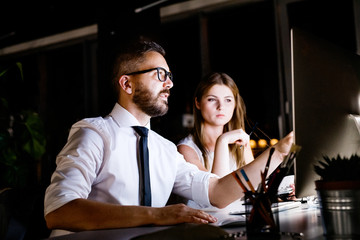 Businesspeople in the office at night working late.