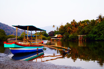 Obraz premium Traditional indian boat near Paloem beach. Small lagoon on the sunset. Excursion boat on the shore.