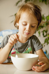 Cute little girl having breakfast muesli with milk at home in the kitchen (healthy food, eating, children, childhood concept )
