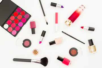 Obraz premium Feminine cosmetics - lipstick, nail polish and accessories on white background. Flat lay, top view. Beauty concept