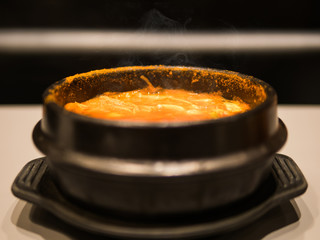 The selective focused and closeup image of hot Kim chi soup in black bowl.