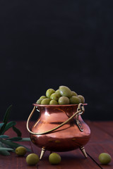 Fresh green olives in the metallic jar on the black background