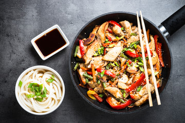 Chicken Stir fry and udon noodles on black. Top view.