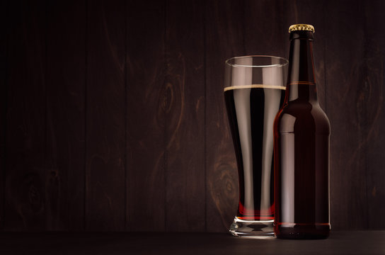 Brown beer longneck bottle and glass weizen with porter on dark wood board, copy space, mock up. Template for advertising, design, branding identity.