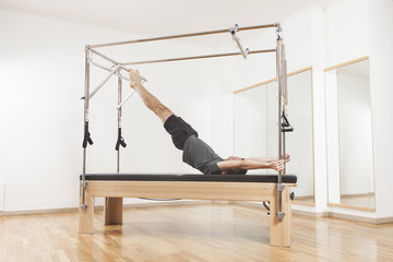 Pilates instructor performing exercise on cadillac equipment