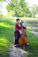 Adult musician woman playing on violoncello outdoors. Music teacher playing cello