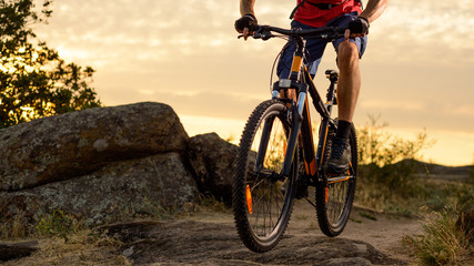 Plakat Cyclist in Red Riding the Bike on the Rocky Trail at Sunset. Extreme Sport and Enduro Biking Concept.