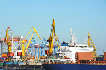 Naklejka premium Bulk cargo ship under port crane