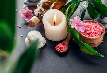 Spa essentials including candle, salt, stones, oil and green leaves