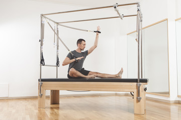 Pilates instructor performing exercise on cadillac equipment