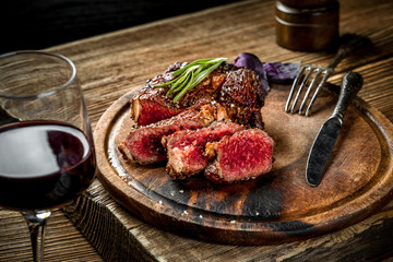 Grilled ribeye beef steak with red wine, herbs and spices on wooden table