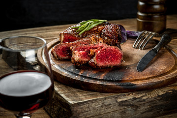 Grilled ribeye beef steak with red wine, herbs and spices on wooden table