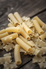 Mixed dried pasta selection on wooden background.