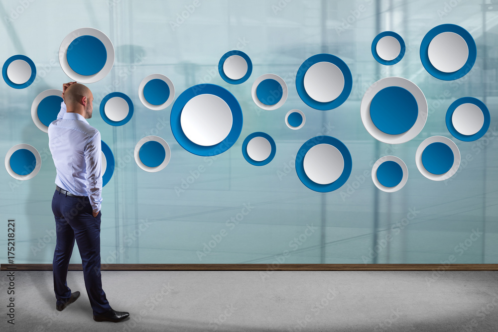 Poster businessman in front of a wall with empty app interface made of blue button displayed on a interface