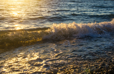 sea pebble beach with multicoloured stones, waves with foam