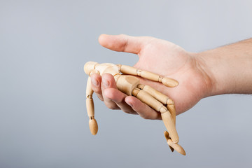 the figure of a wooden man lies the hand of a man