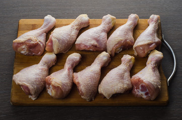 Fresh raw chicken legs arrangement on kitchen cutting board