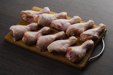 Fresh raw chicken legs arrangement on kitchen cutting board
