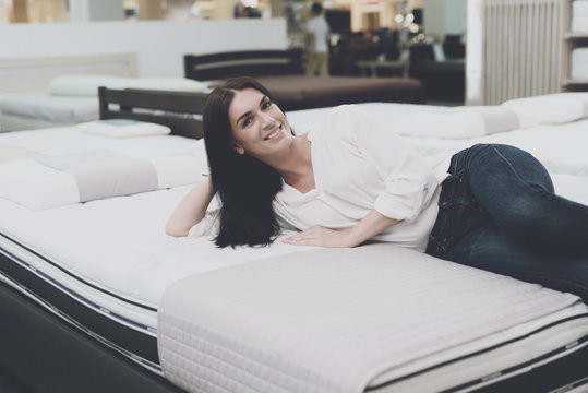 A woman chooses a mattress in a store. She decided to lie down and try it