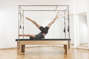 Pilates instructor performing exercise on cadillac equipment