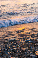 Amazing sea sunset on the pebble beach, the sun, waves, clouds