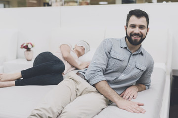 The woman put on a blindfold on her eyes and fell asleep on the bed in the store. A man is lying next to her and smiling