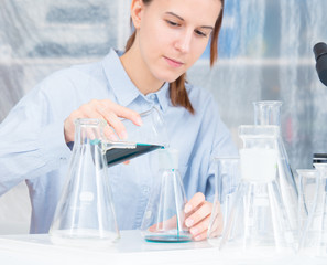 A female laboratory assistant mixes reagents in a chemical laboratory