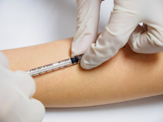 Close-up macro detail of a physician performing a BCG vaccination using an insulin syringe on the forearm of a child. Healthcare and medicine concept.