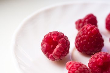 raspberries on a white saucer close up