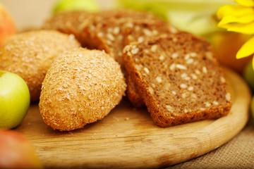 Fresh bread. Pieces of bread with sunflower seeds. Loaf of wholemeal bread and sliced  pieces are on the table. Apple, sunflower, pieces of bread, table, bun, corn - autumn concept advertising bread.