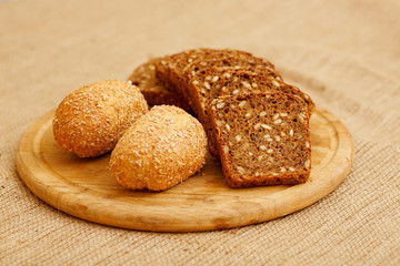 Biscuits baked from flour and bran. Cut pieces of black crusty bread. Diet bread useful for a healthy diet. Different types of bread is piled on the table in the composition. White and brown bread.