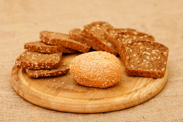 Biscuits baked from flour and bran. Cut pieces of black crusty bread. Diet bread useful for a healthy diet. Different types of bread is piled on the table in the composition. White and brown bread.