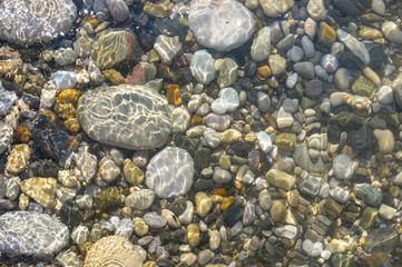 sea pebble beach with multicoloured stones, waves with foam