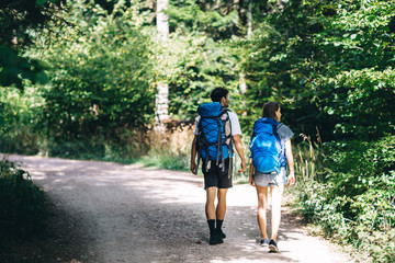 Fototapeta na wymiar Hiking couple. Young couple with backpacks walking through the forest 